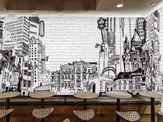 a wall mural in a restaurant with chairs and stools next to it that has a cityscape drawn on the wall