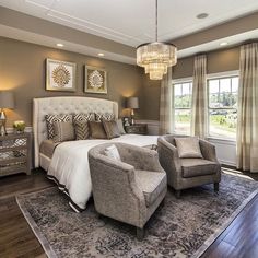 a large bed sitting in the middle of a bedroom next to two chairs and a table