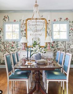 a dining room table with blue chairs and a chandelier hanging from the ceiling