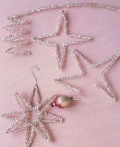 some ornaments are laying on a pink surface