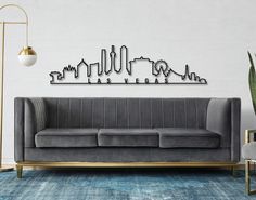 a living room with a gray couch and metal city skyline wall art on the wall