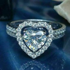 a heart shaped diamond ring on top of a blue surface