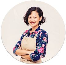 a woman with an apron standing in front of a white circle holding her arms crossed