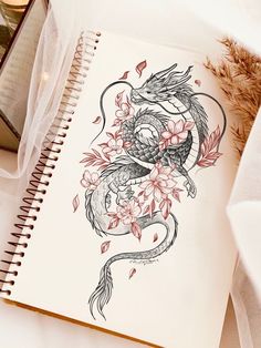 an open notebook with a dragon and flowers on it