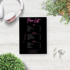 a black menu with pink lettering on it next to headphones and plant in the background