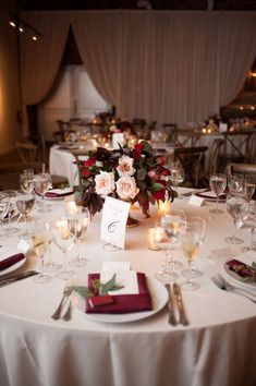 the table is set with white linens, silverware and candles for an elegant wedding reception