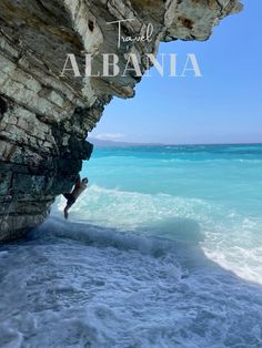 a person standing on the edge of a cliff next to the ocean with text overlay that reads travel to albania