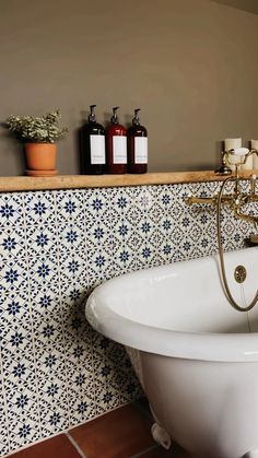 a bath tub sitting in the middle of a bathroom next to a shelf with bottles on it