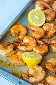 shrimp and lemon on a baking sheet ready to be cooked in the oven or served