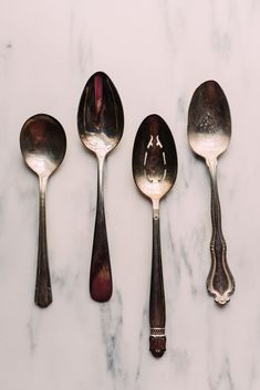 four spoons and two forks on a marble surface