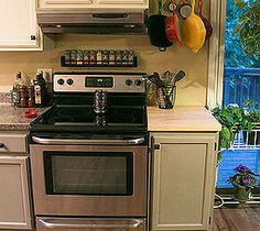 a stove top oven sitting inside of a kitchen next to white cabinets and wooden floors