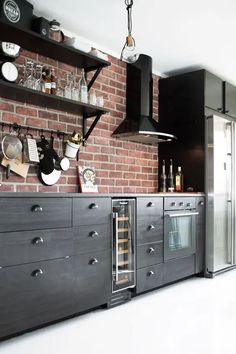 a brick wall in a kitchen with stainless steel appliances and wine glasses on the shelves