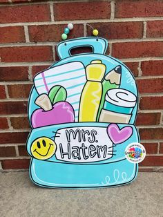 a blue backpack with school supplies on it and the words mrs hatten written in white