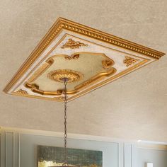 a chandelier hanging from the ceiling in a room with white walls and gold trim