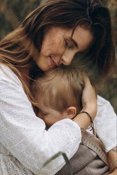 a woman holding a baby in her arms while she holds the child's head