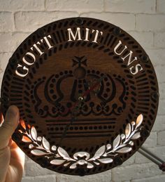 a person holding up a wooden clock with the words gott mit ums on it