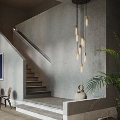 a modern staircase with chandelier, table and chairs in the room next to it