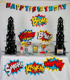 an image of a birthday party setting with comic signs on the table and decorations around it