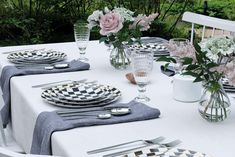 the table is set with plates, silverware and flowers in vases on it