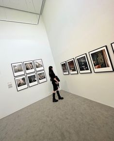 a woman standing in front of a wall with pictures hanging on it's sides