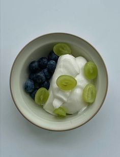 a bowl filled with yogurt, grapes and blueberries