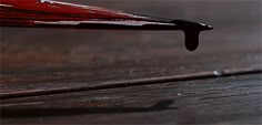 a red umbrella sitting on top of a wooden floor next to a puddle of water