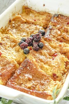 a casserole dish with berries and powdered sugar on top, ready to be eaten