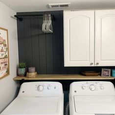 two white washers sitting next to each other in a laundry room with black walls