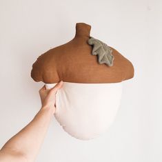 a person is holding up a brown and white pillow with leaves on the back of it