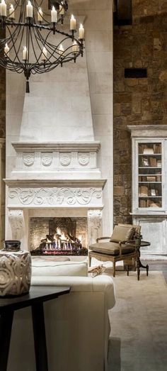 a living room filled with furniture and a fire place under a chandelier hanging from the ceiling