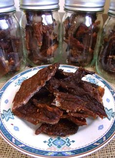 a plate topped with pieces of beef next to glass jars