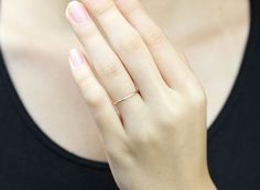 a woman wearing a black shirt holding her hand up to her face with a diamond ring on it