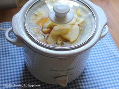 an open crock pot filled with apples on top of a blue and white checkered table cloth