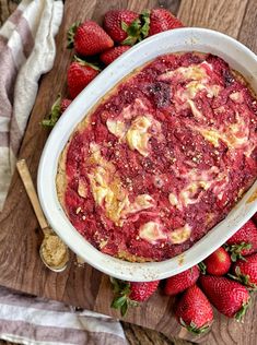 a bowl of strawberry cheesecake on a cutting board with strawberries