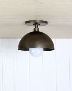 an overhead light hanging from the ceiling in a room with white walls and wood paneling