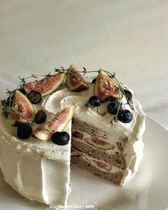 a cake with white frosting and fresh fruit on top is cut in half to show the inside