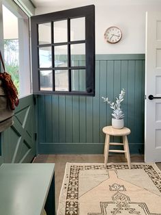 a room with a chair, rug and clock on the wall next to it's windows