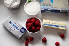 ingredients to make cheesecake sitting on a counter with raspberries, butter and flour