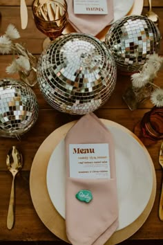 the table is set with silver and pink plates, napkins, and disco balls