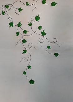 a branch with green leaves hanging from it's sides on a wall in a room