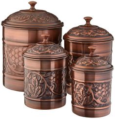 three copper colored canisters with ornate designs on the top and bottom one has a lid