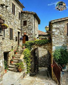 an alley way with stone buildings and plants growing on the steps leading up to it