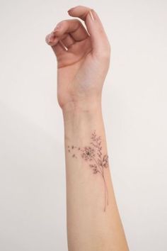 a woman's arm with a small flower tattoo on the left side of her wrist