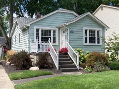 a small blue house with flowers in the front yard