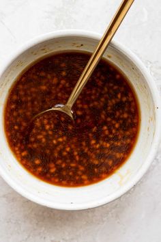 a white bowl filled with chili sauce and a wooden spoon in the bowl next to it