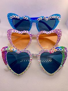 three heart shaped sunglasses with colorful crystals on them