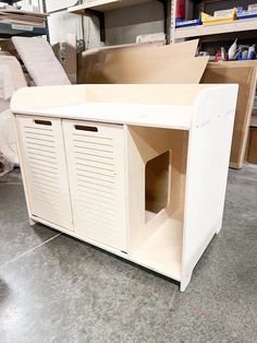 an unfinished cabinet is sitting in the middle of a room with shelves and other items