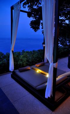 a canopy bed sitting on top of a patio next to the ocean