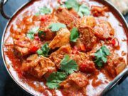 a close up of a bowl of food with meat and vegetables in it on a table