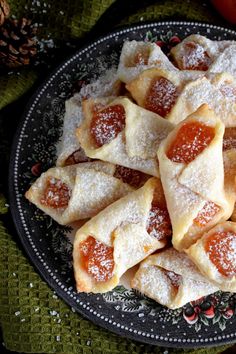 a plate full of pastries covered in powdered sugar on a green table cloth